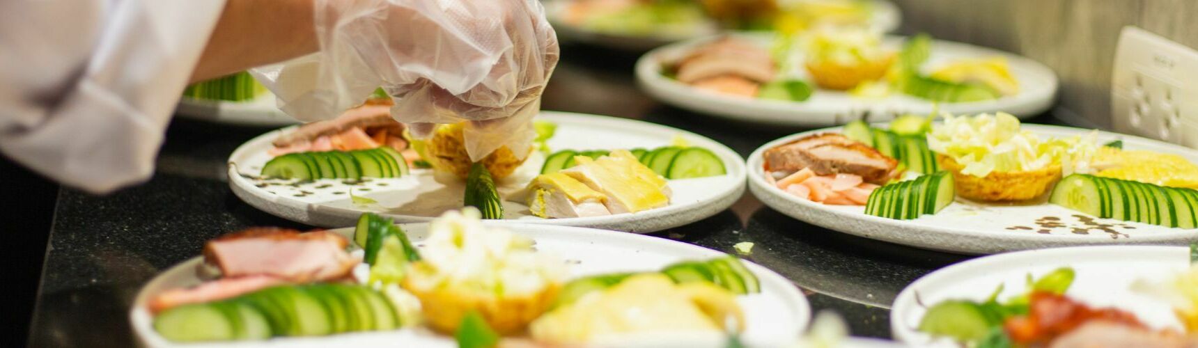 Hospitality food waste. Row of plates with chef plating up luxury meals.