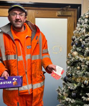 J&B Recycling team member next to Christmas tree at head office