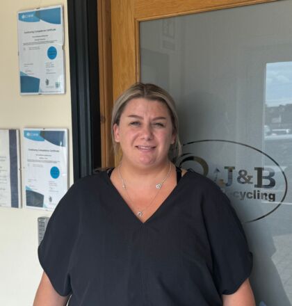 J&B Recycling team member in corridor next to glass door with logo