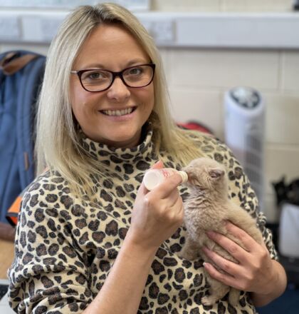 A staff member of J&B Recycling feeding a baby kitten