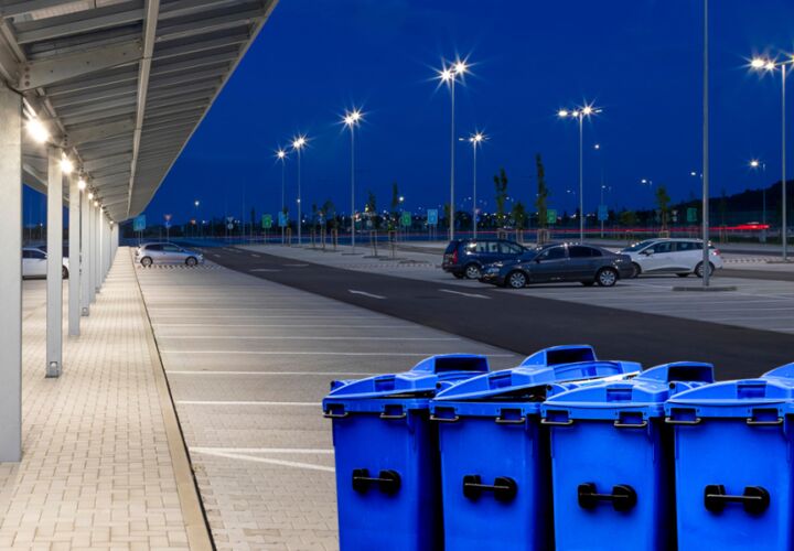 Photo of large wheelie bins in a large car park, promoting commercial waste services