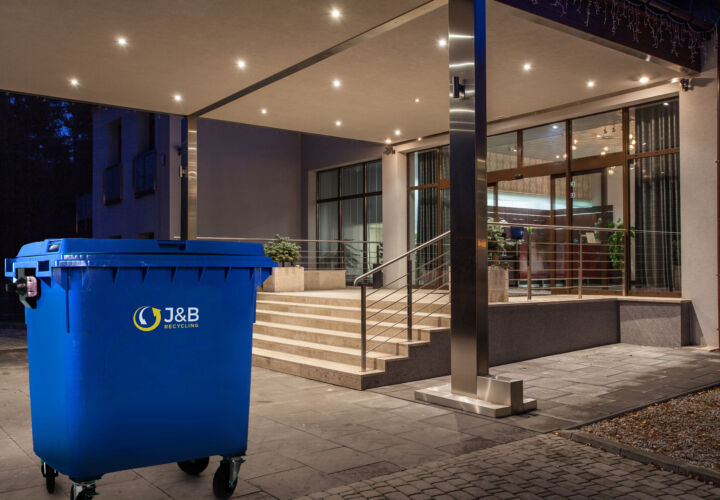 Large wheelie bin outside hotel. Blue recycling bin with J&B recycling logo