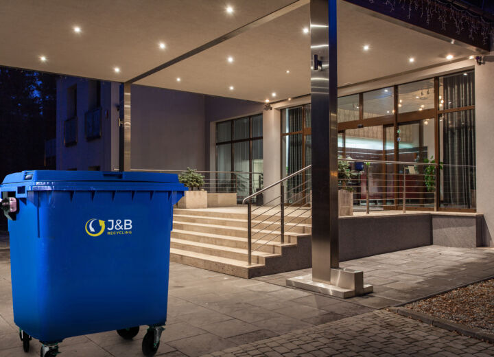 Large wheelie bin outside hotel. Blue recycling bin with J&B recycling logo